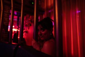 Moody red-lit interior scene with dramatic lighting and shadows.