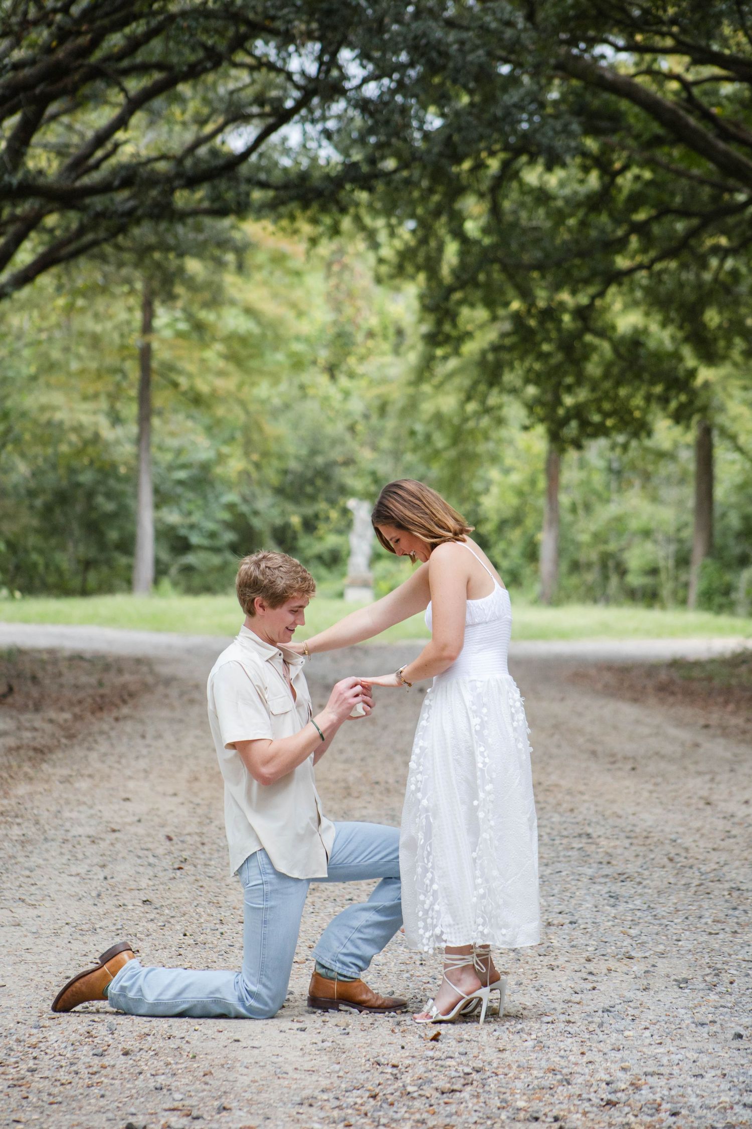 A romantic marriage proposal takes place on a tree-lined dirt path as a couple shares a special moment together.
