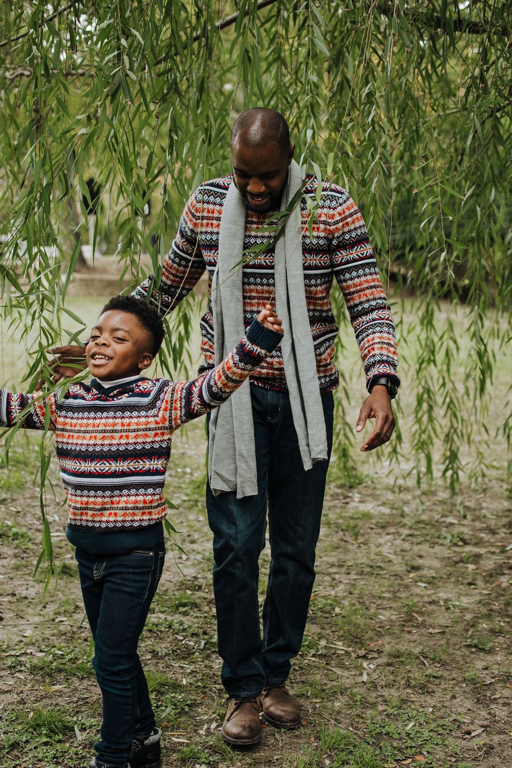 Playful interaction under weeping willow trees in natural outdoor setting.
