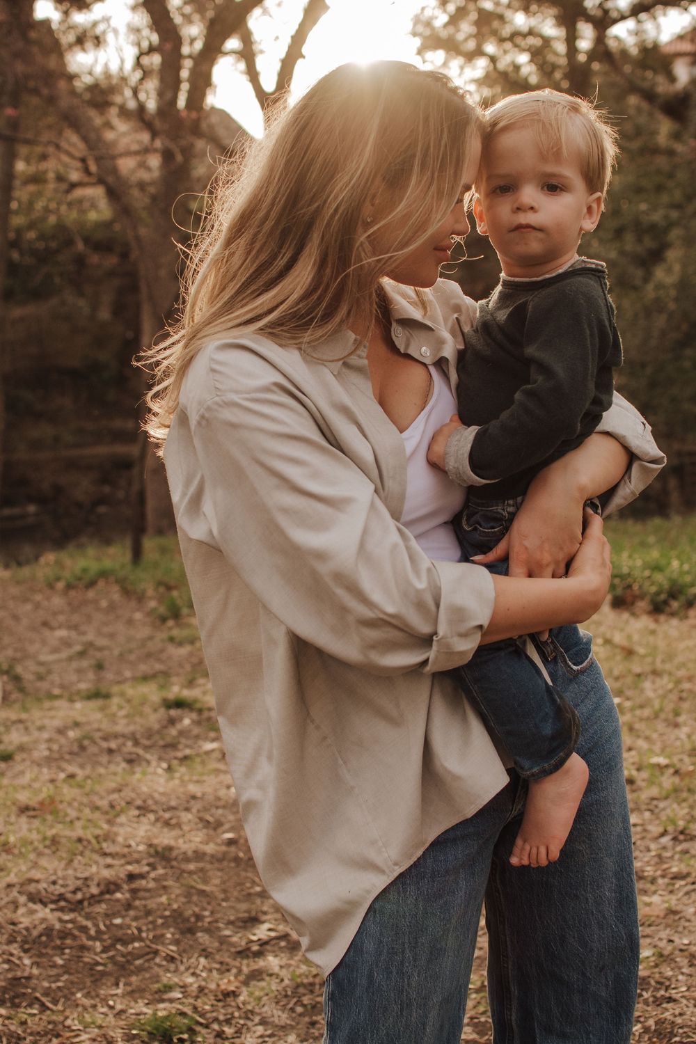 A parent shares an intimate outdoor moment with their young child in warm afternoon light. Dallas Texas