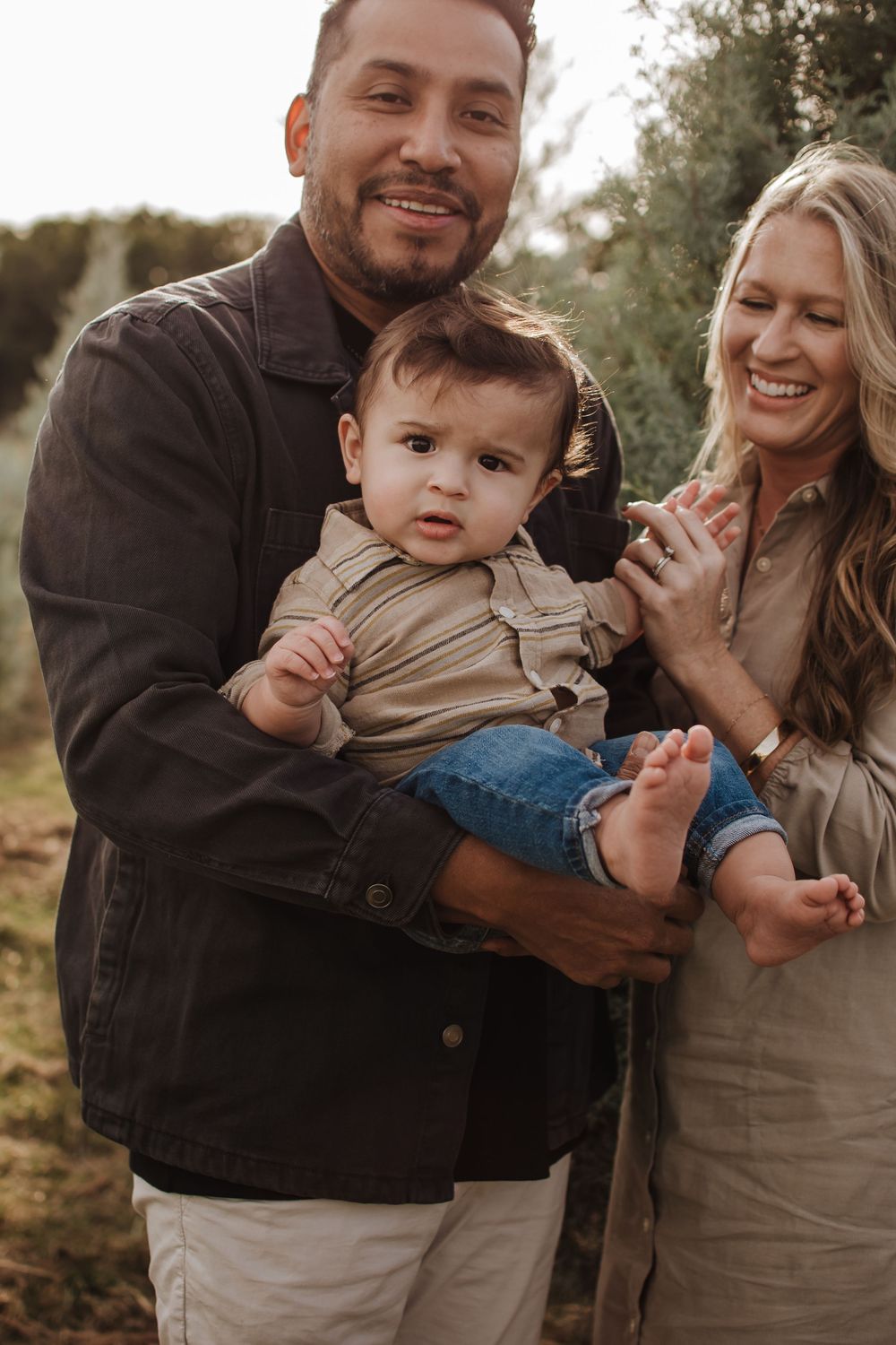 Family shares joyful moment together outdoors in earth-toned clothing. Texas Tree Farm Near DFW