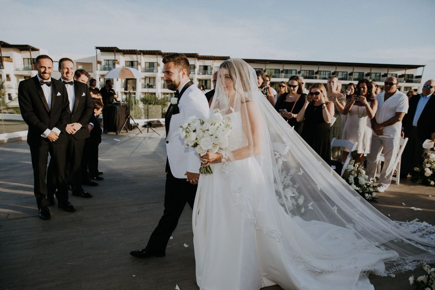 Wedding ceremony processional on modern rooftop venue with white floral decorations.