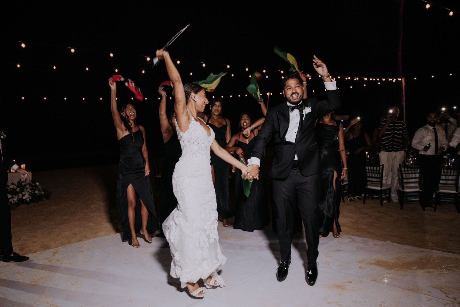 Wedding celebration features synchronized dancing on a lit outdoor dance floor.