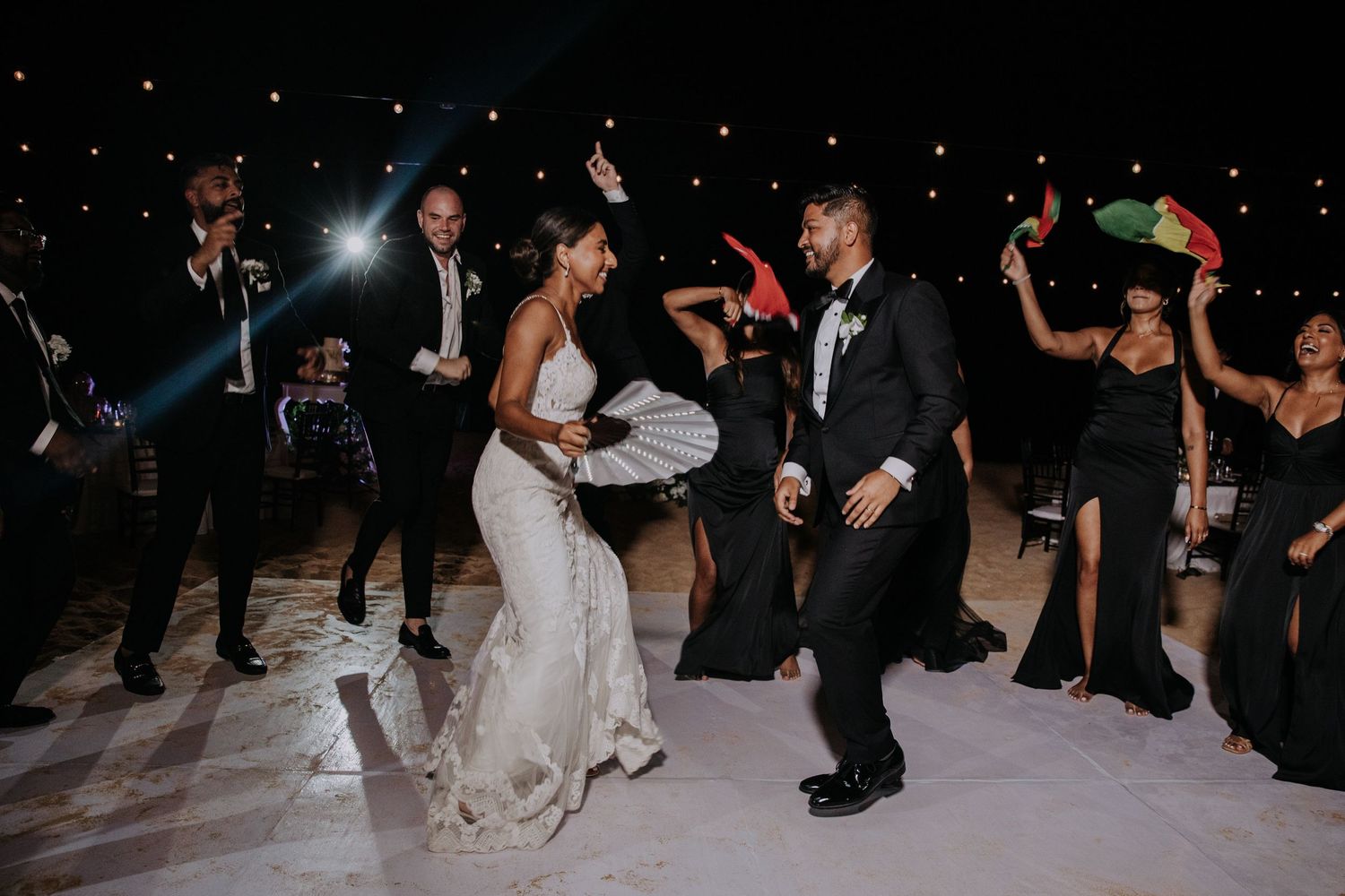 Guests perform energetic dance routine during nighttime wedding celebration.