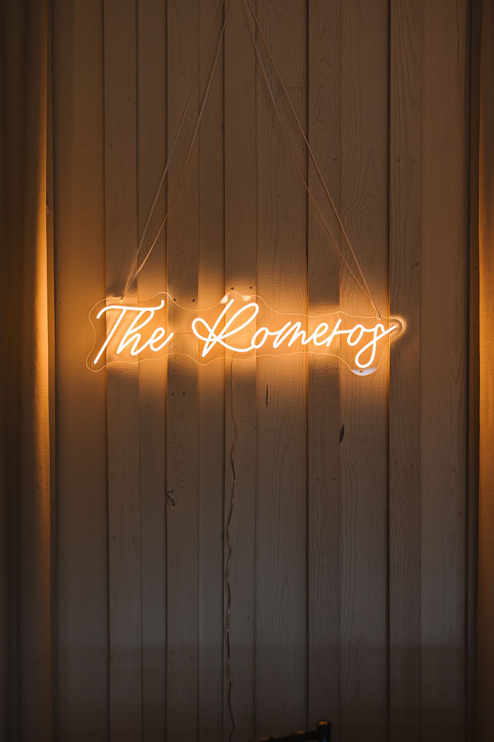 Glowing neon cursive sign reading 'The Rooftop' mounted on a white wooden wall with warm ambient lighting.