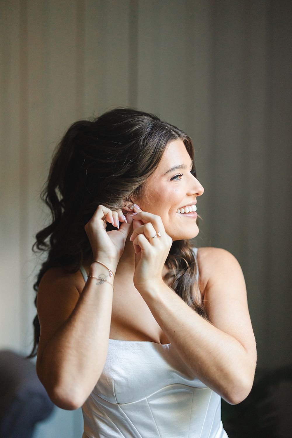A sequence of getting-ready moments shows someone adjusting earrings while wearing a white dress.