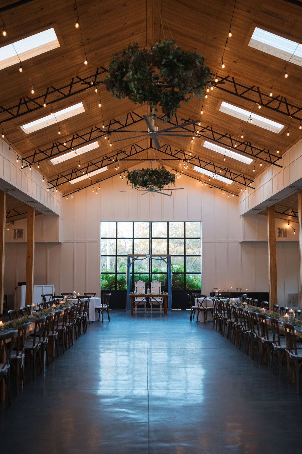 Modern rustic event venue with exposed wood beams, skylights and large windows showcasing an expansive open floor plan.