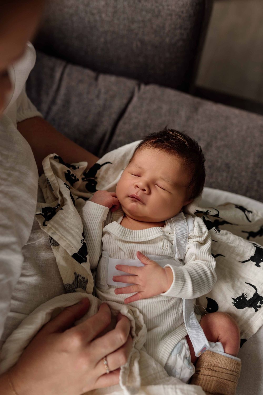 Little newborn boy sleeping in mothers arms during photoshoot