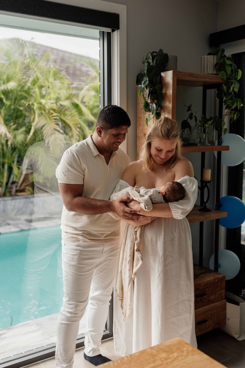 Natural newborn photography in Sydney’s Hills District with mum holding baby boy by window.