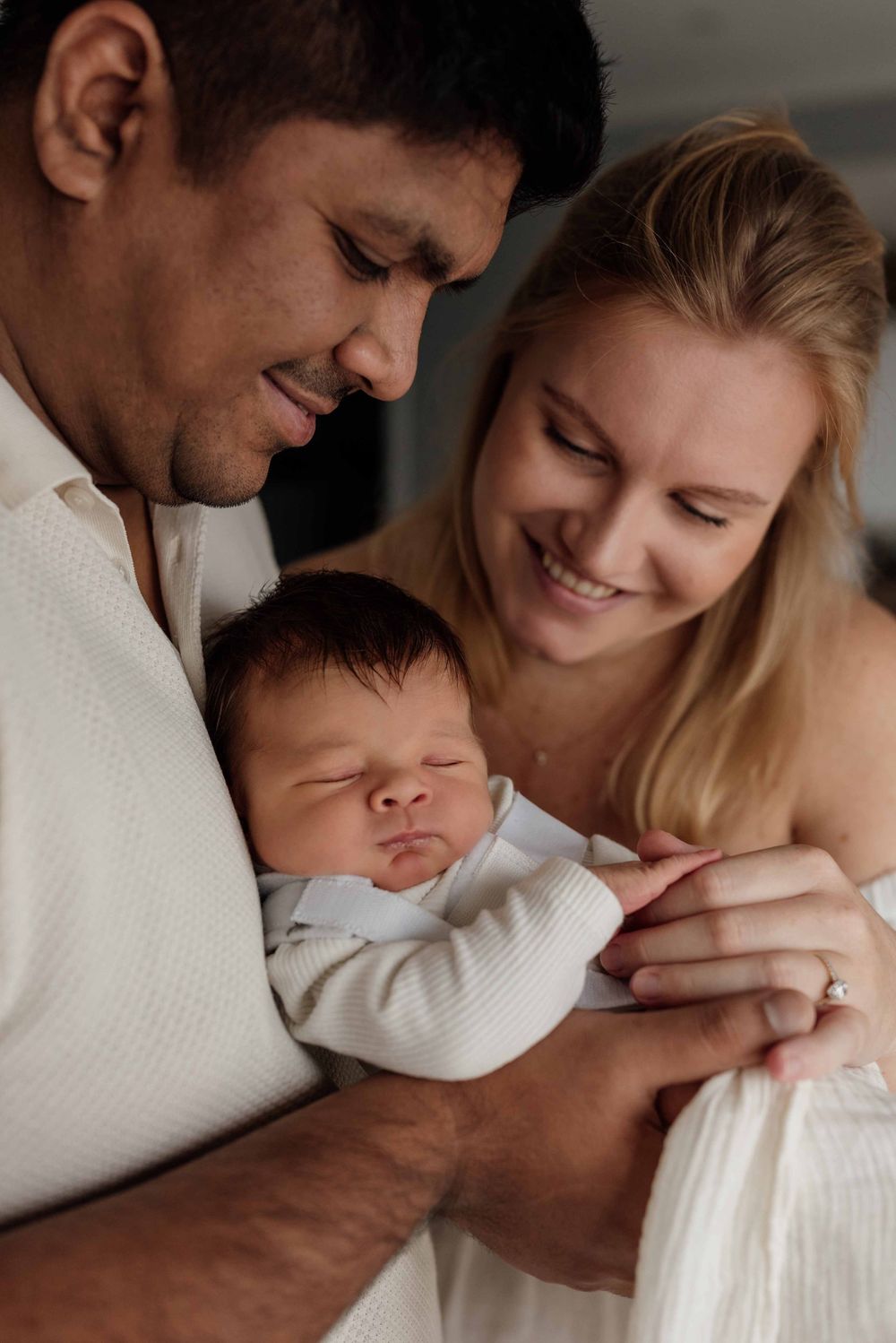 Baby boy resting on parents’ chest in warm family moment during Sydney newborn session.