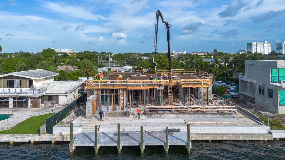 Panoramic view of waterfront construction site with cranes and wooden framing structure in progress.