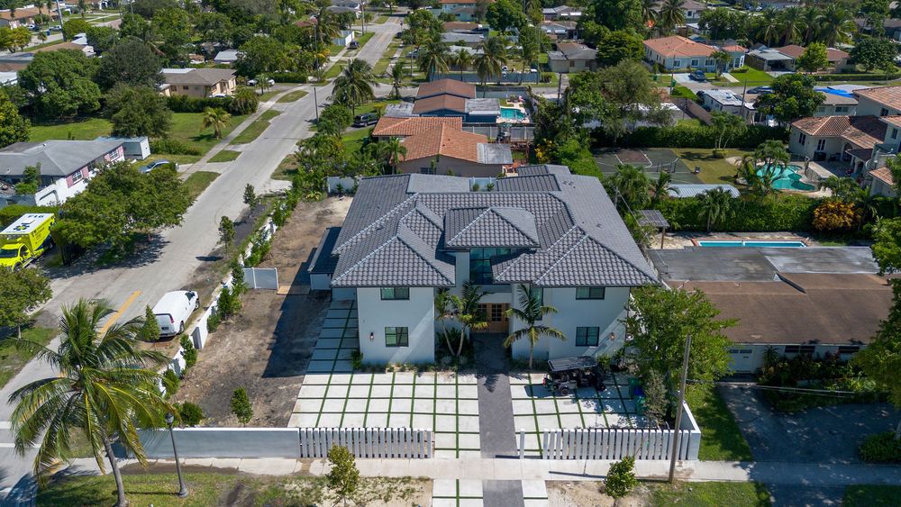 Panoramic aerial view of waterfront luxury homes with pools and boats in a Miami residential neighborhood.