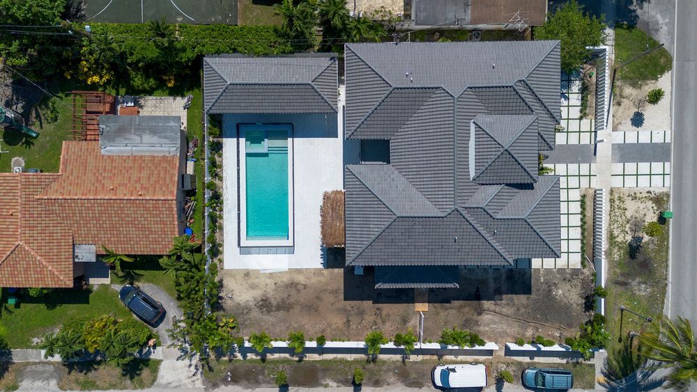 Overhead drone shot of modern waterfront homes with private docks along canal in Miami residential area.