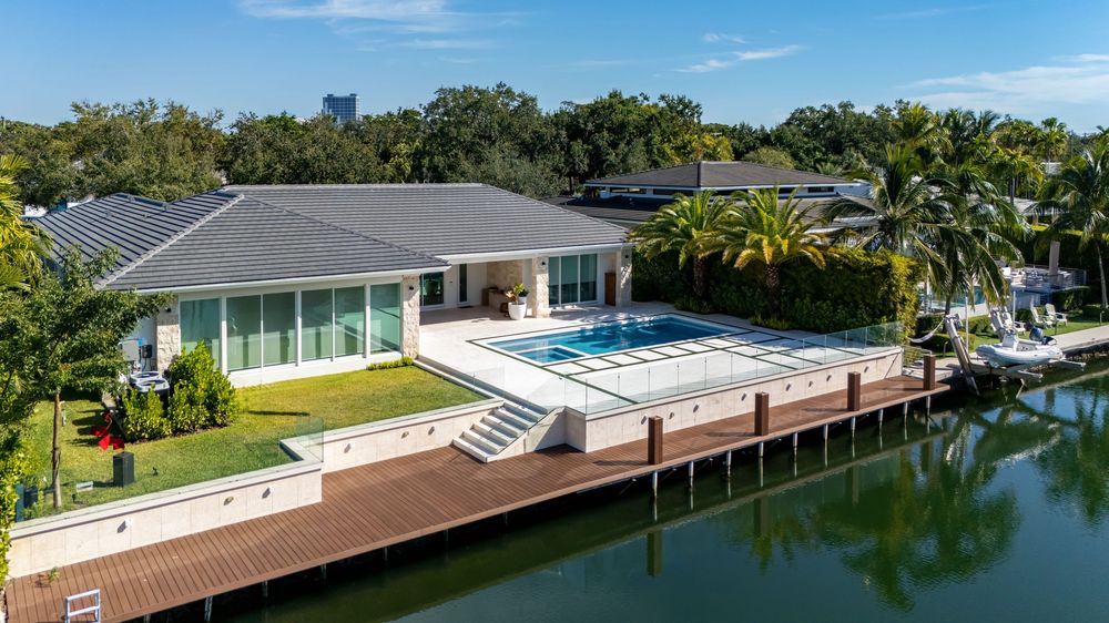 Panoramic waterfront view showing luxury homes with private docks along Miami canal under blue skies.
