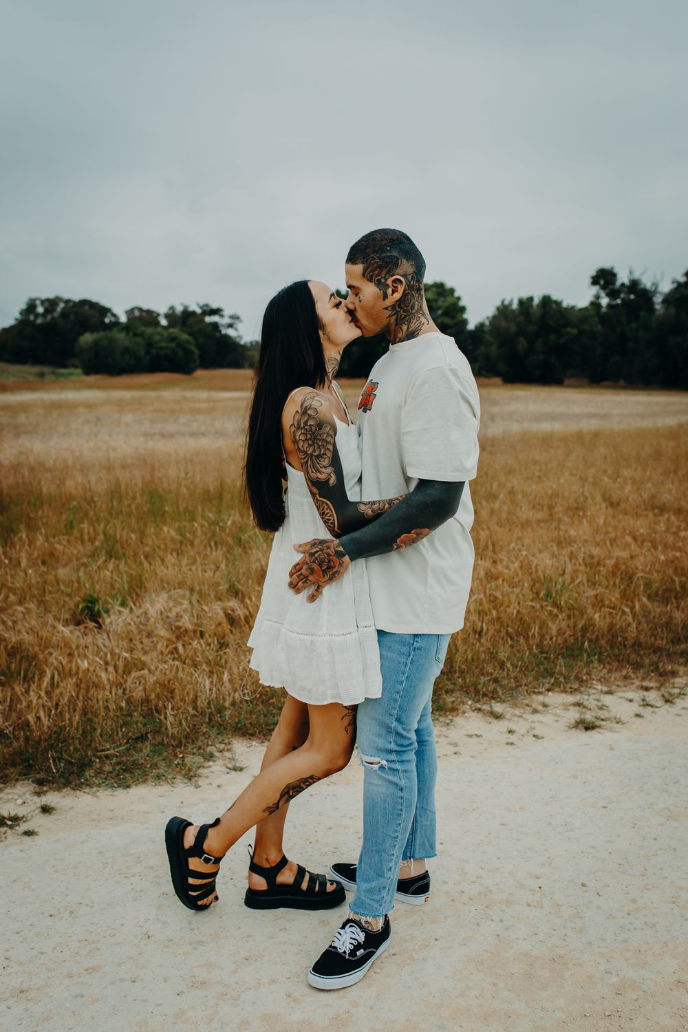 A romantic couple embraces and dances together in a golden wheat field at sunset.
