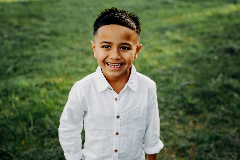 A collection of outdoor portraits on a grassy field showing a person wearing a white button-up shirt.