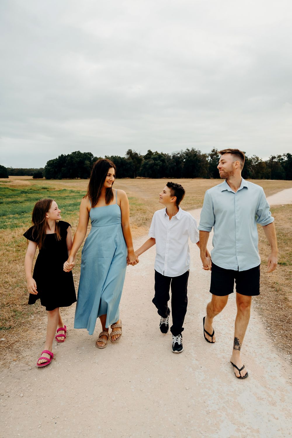 Family walking together on a dirt path holding hands and looking behind them as they create memories outdoors.