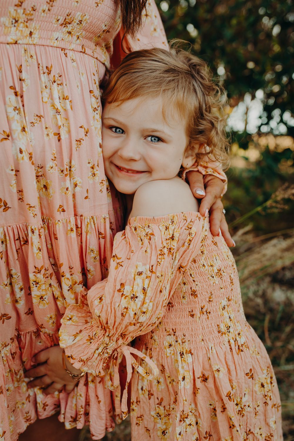 Three candid photographs showing matching pink floral dresses in warm outdoor lighting.
