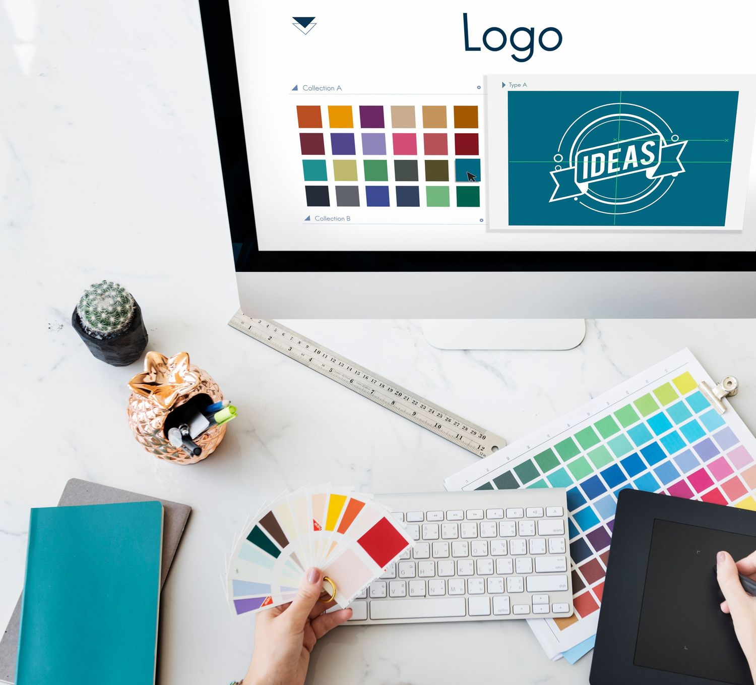 Design workspace showing color palette samples and keyboard with teal notebook.