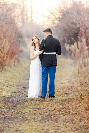 A romantic moment between a couple in formal attire walking along a misty autumn path.