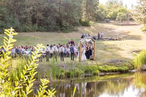 Wedding guests gather near a scenic pond surrounded by natural landscaping.