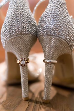 Sparkly silver wedding heels with crystal embellishments on wooden floor.