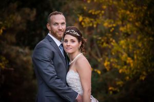 A romantic autumn wedding portrait with fall foliage in the background.