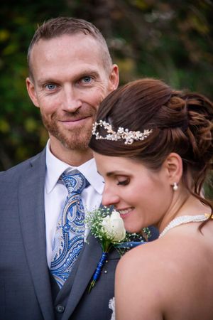 An intimate wedding portrait featuring a blue paisley tie and delicate bridal accessories.