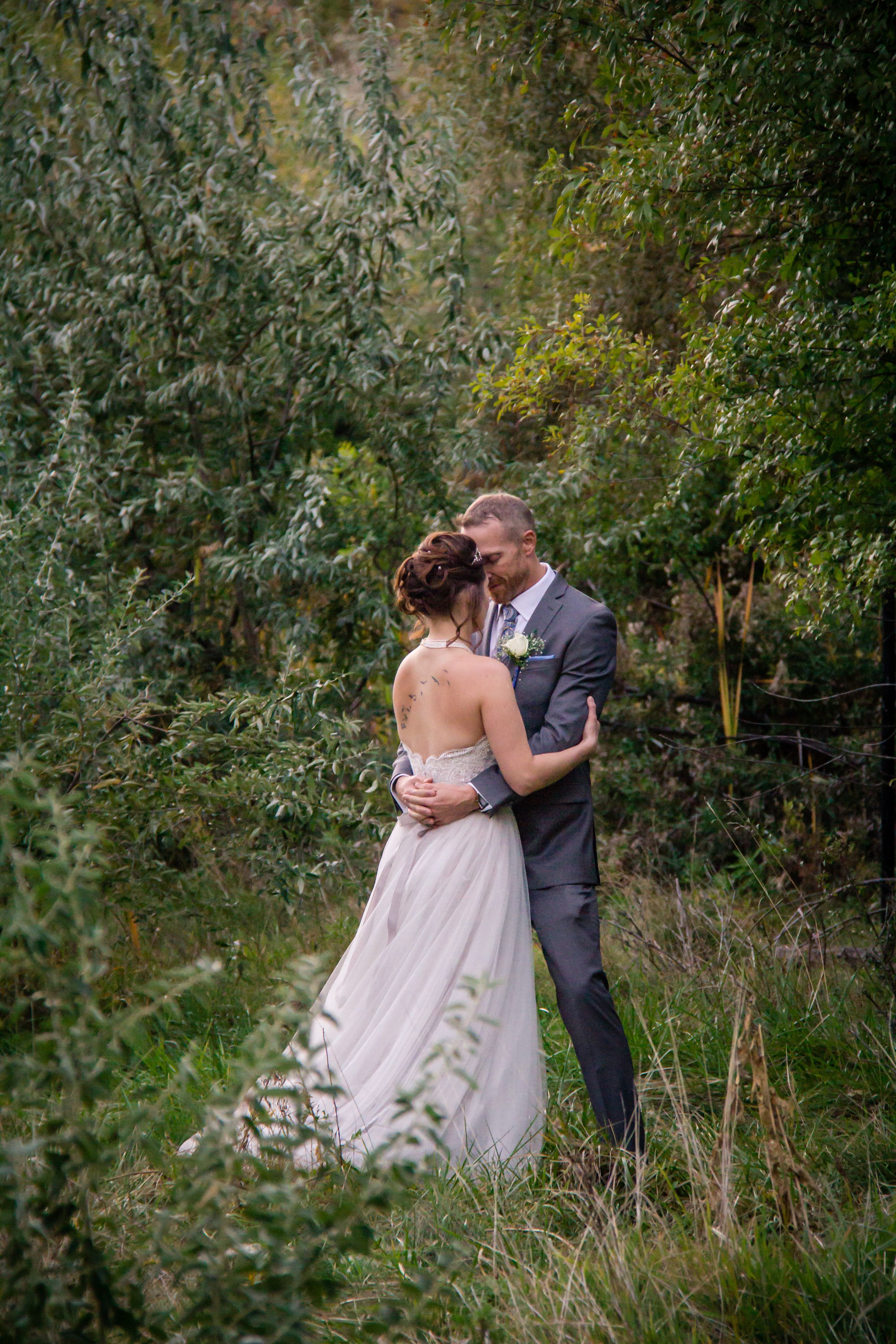 A romantic couple embraces in a lush garden setting during a wedding photoshoot.