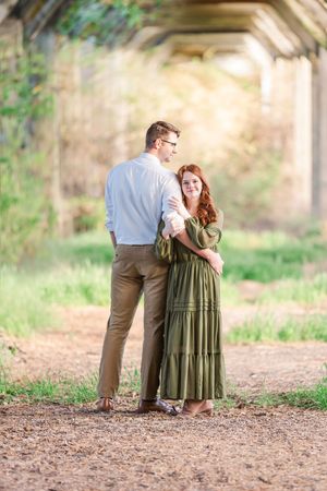 Couple shares tender moment on dirt path during outdoor photo session.