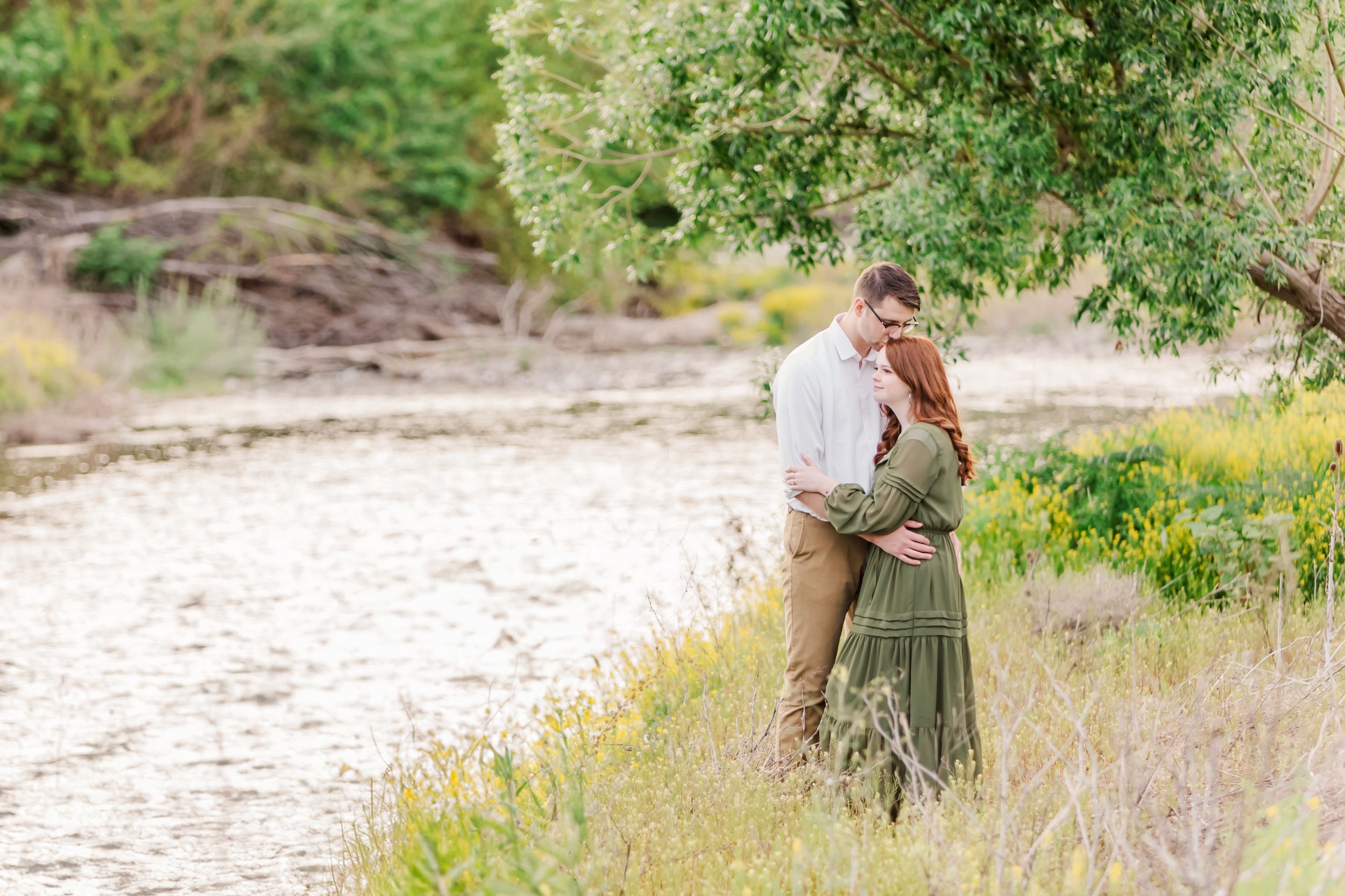 Couple poses together in a natural outdoor setting with soft lighting.