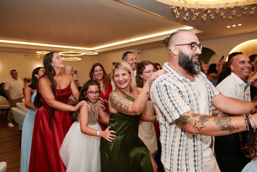 Guests form a conga line and dance together at a festive wedding reception in an elegant ballroom.
