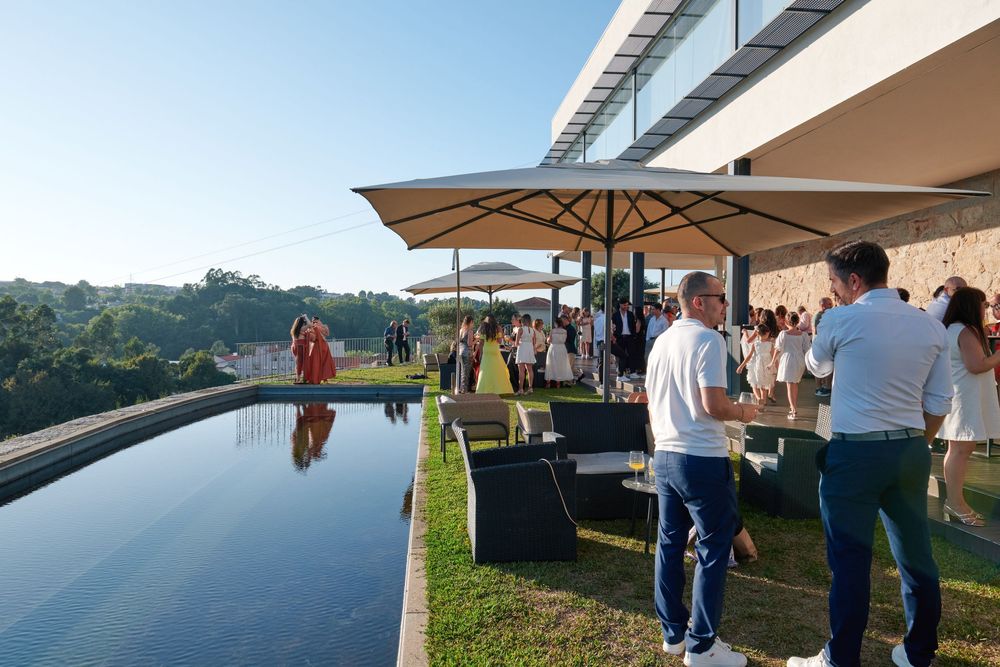 Elegant outdoor poolside party at a luxury villa with guests mingling under umbrellas at golden hour.