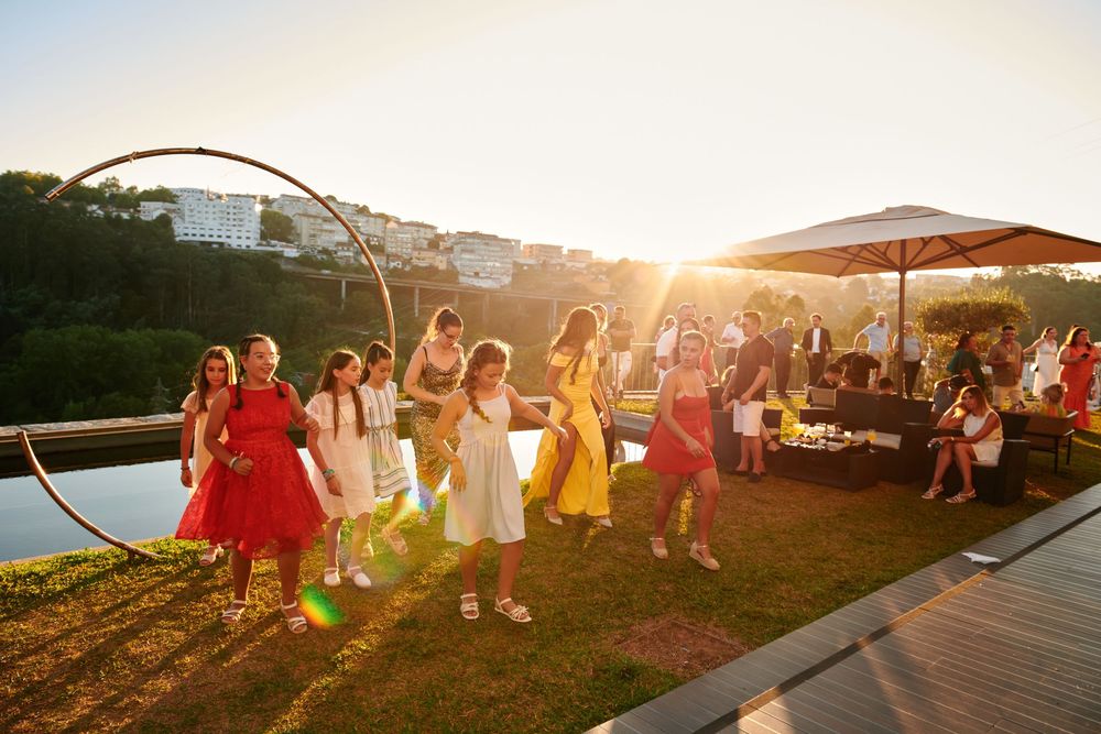 Children and adults dancing joyfully on a lawn at a vibrant outdoor sunset celebration.