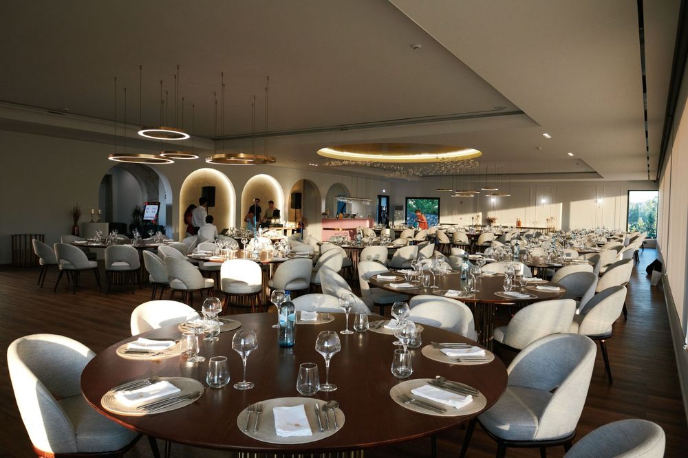 Elegant banquet hall with round tables, white chairs, and warm circular ceiling lighting for a formal event.