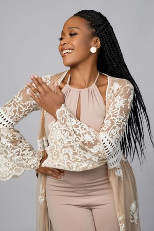 A woman in a white lace blouse against a gray background poses in a series of four expressive fashion shots.