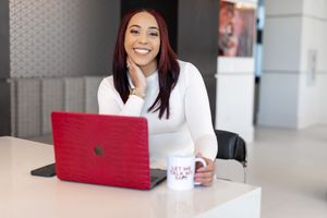 Professional working on red laptop with coffee cup in modern office space.