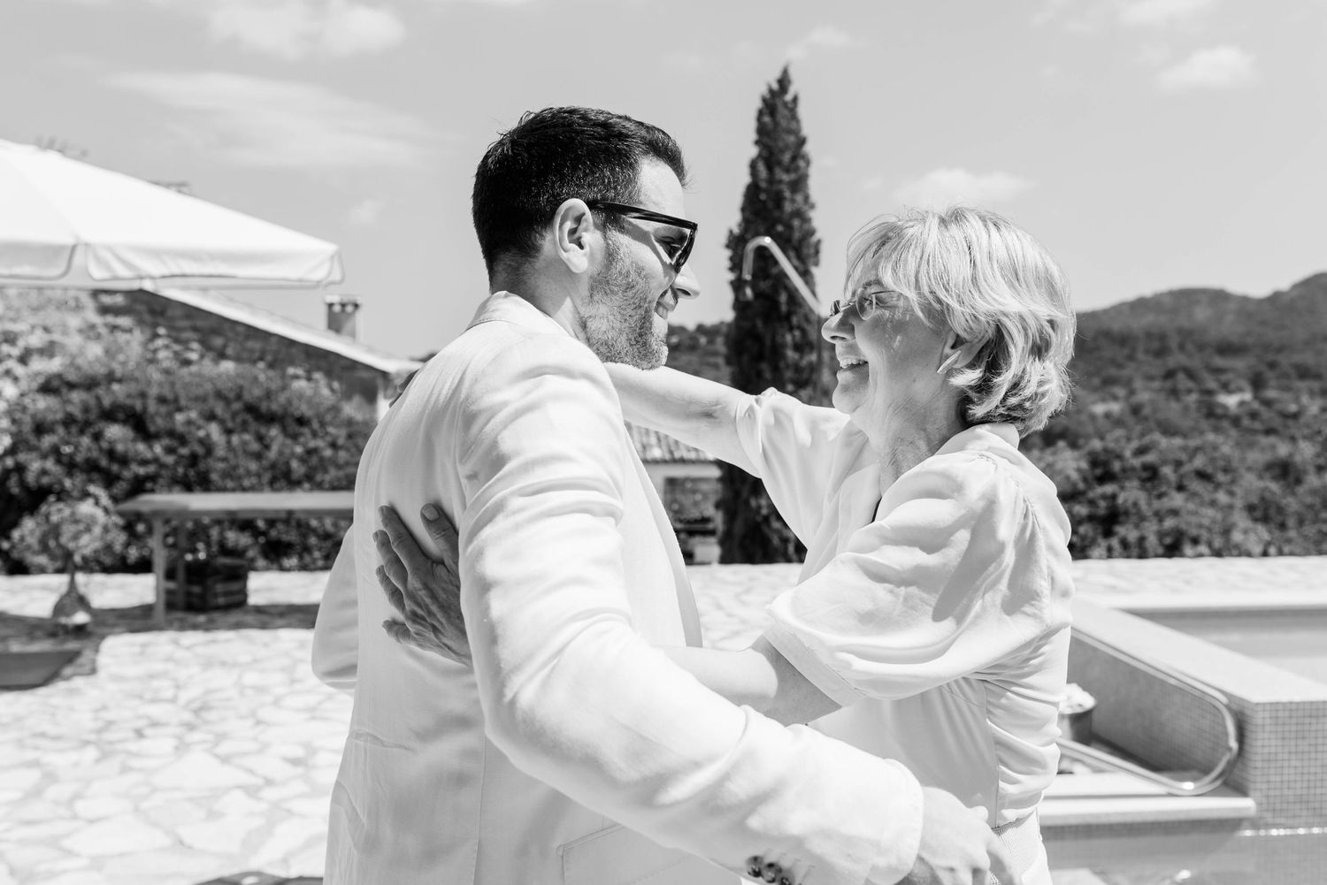 Happy couple shares a romantic moment on a sunny beach in white wedding attire.