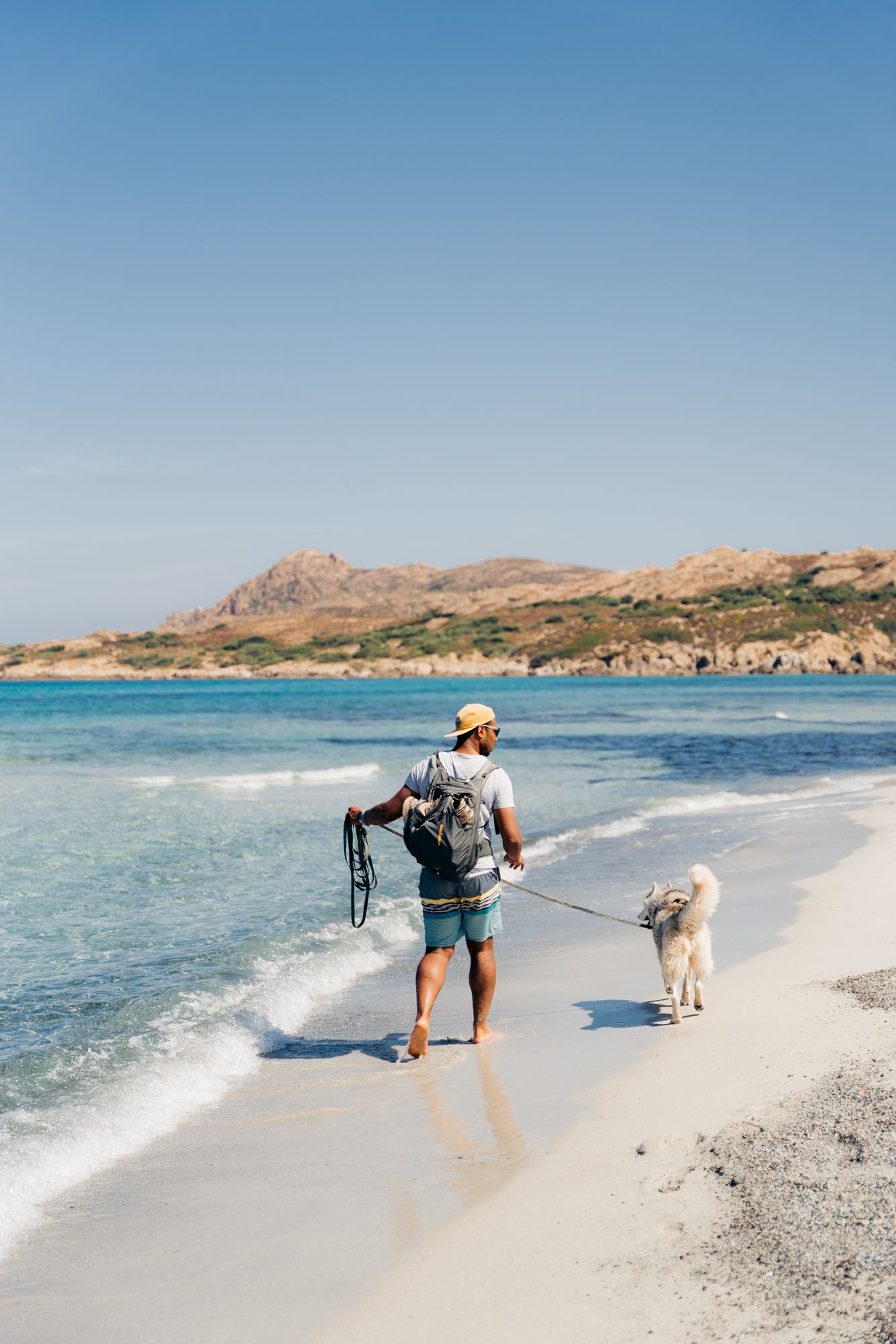 randonneur et son chien qui marche sur la plage de l'ostriconi dans les désert des agriates