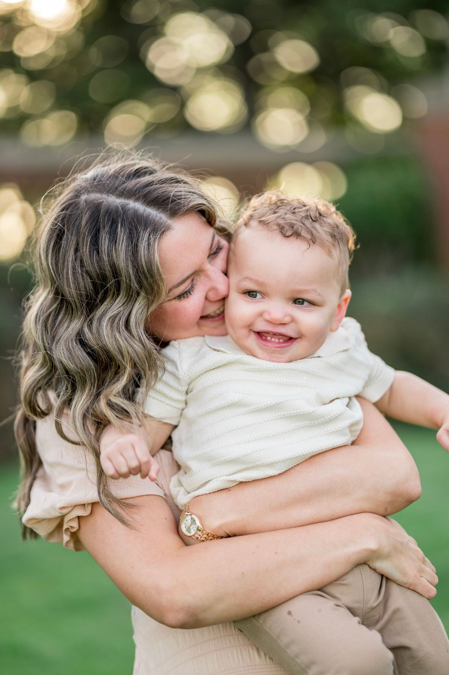 Mother and child share joyful moments in a sunlit outdoor setting with bokeh background effect creating warm ambiance.