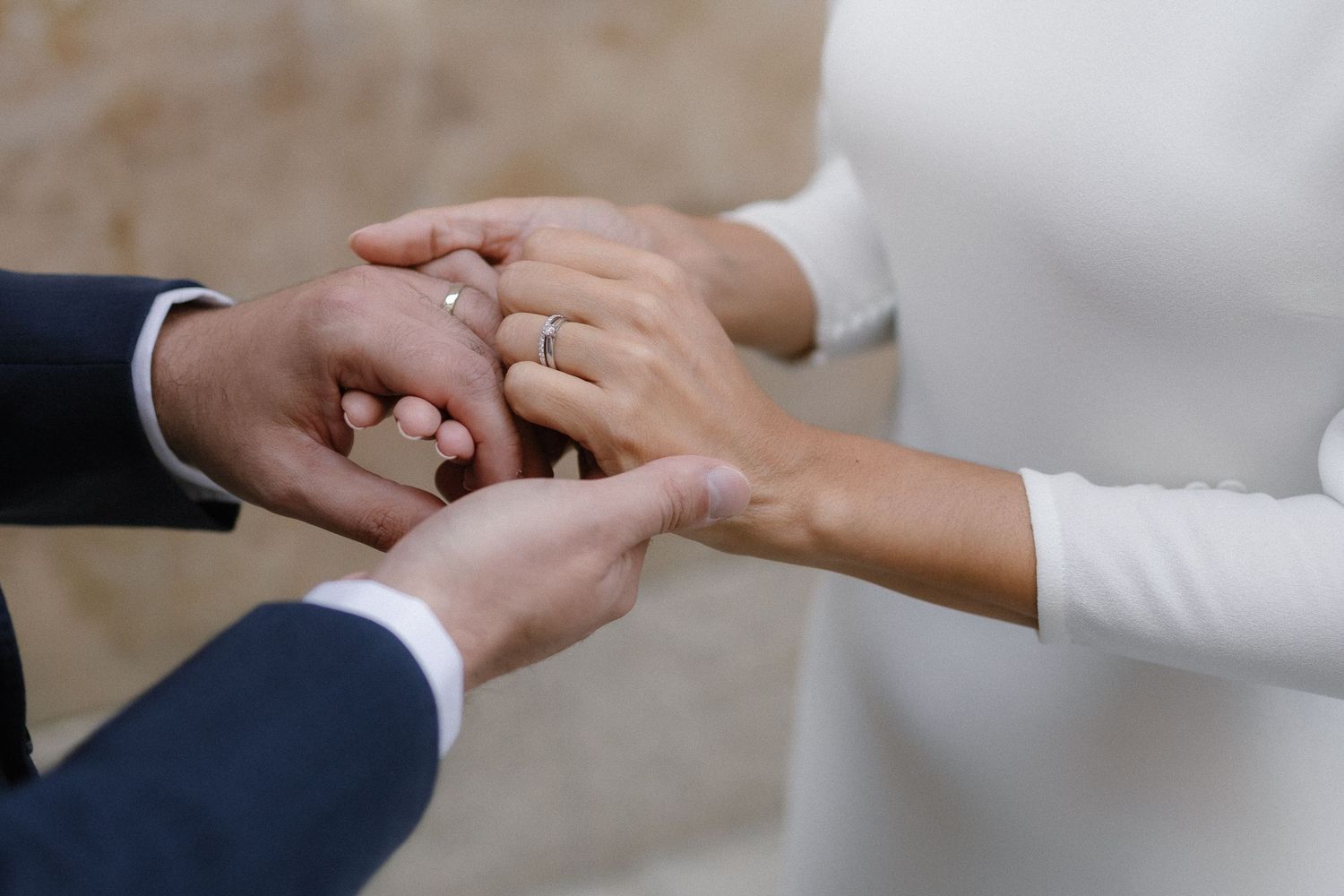 A close-up sequence of hands exchanging wedding rings during a marriage ceremony.