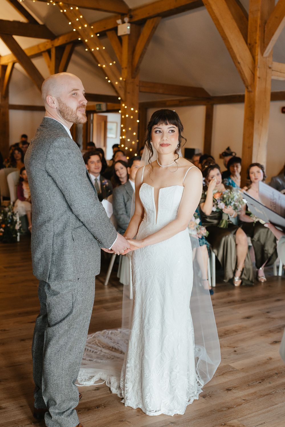 A couple shares their first dance during an intimate wedding reception in a rustic barn venue with twinkle lights.