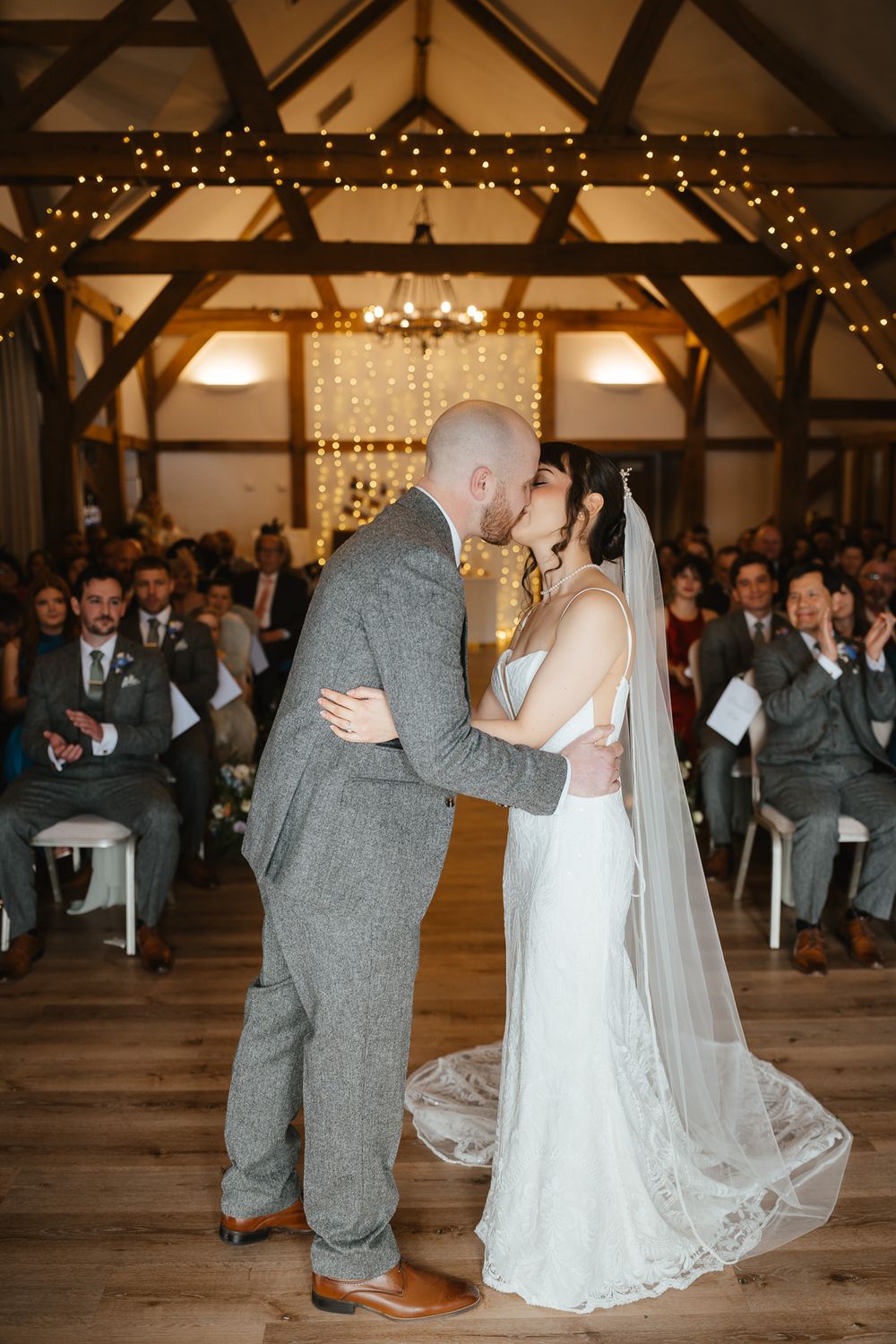 Romantic first dance sequence of newlyweds in a rustic barn venue decorated with string lights and exposed beams.