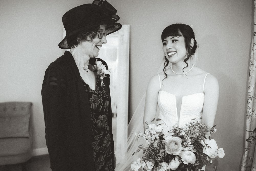 A heartwarming black and white moment between two people on a wedding day as they admire a floral bouquet.