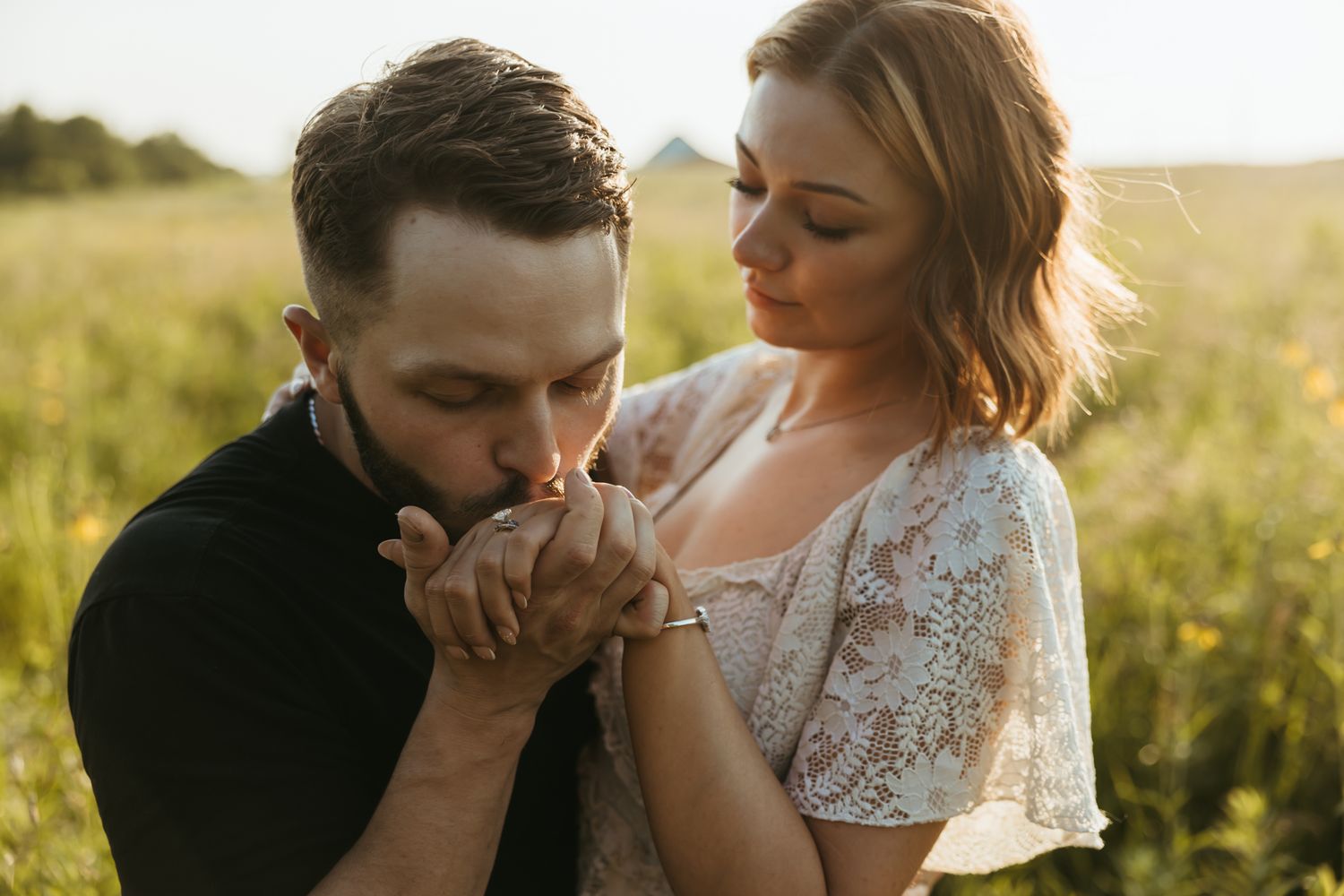 A romantic couple shares intimate moments during their golden hour wedding photo session in a sunlit field.