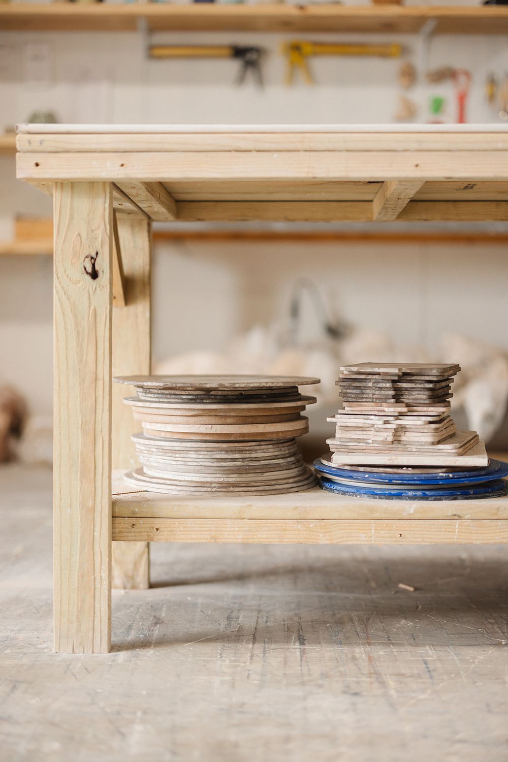 Wooden workshop shelves store circular saw blades and cutting discs arranged in neat stacks.