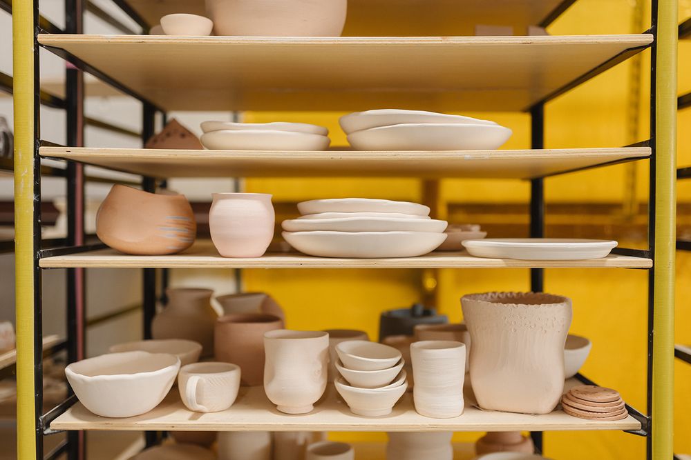 White ceramic bowls and plates neatly arranged on yellow metal shelving units in a retail display setting.