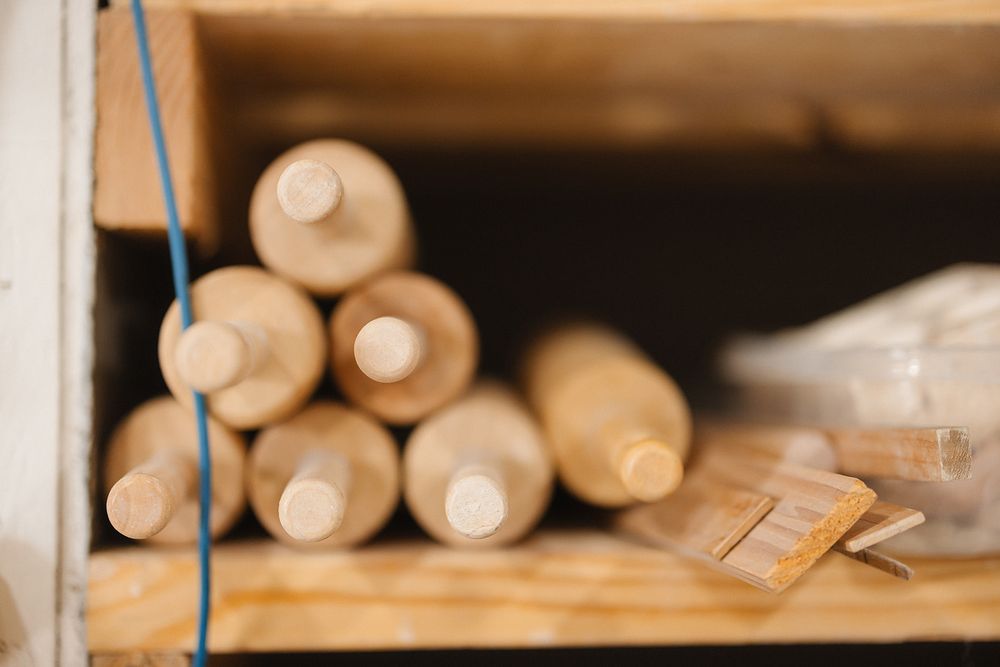 Rolled shipping tubes or documents stacked on a wooden shelf with a blurred tag visible.