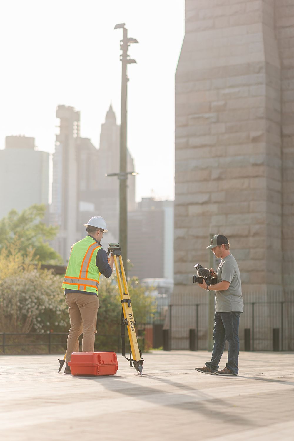 Construction workers surveying and measuring at an outdoor site with equipment during golden hour lighting.