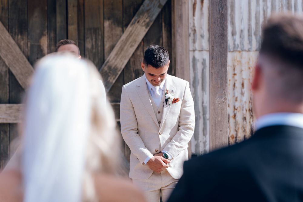 A wedding couple embraces inside a rustic wooden barn venue during their ceremony.